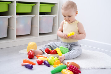Cute kid girl playing in colorful plastic toys vegetable at home. Early childhood development