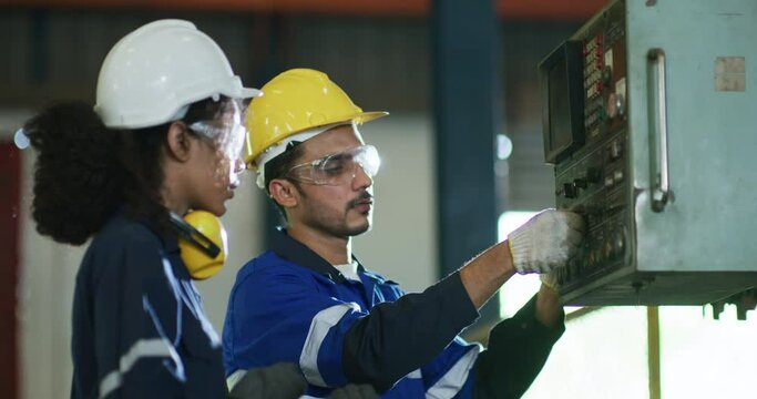 UntitleIndustrial engineer, technician worker wearing uniform, safety hard hat using tablet computer checking control automated robotic arm machine in factory. Automatic manufacturing