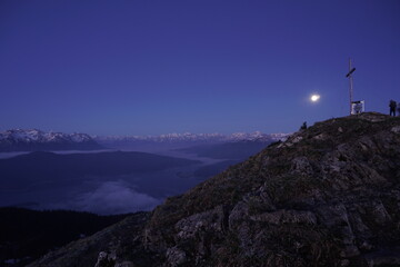 Der Mond steht über dem Gipfel. Im Tal liegt noch immer der Nebel. Doch der Anbruch eines neuen Tages steht kurz bevor.