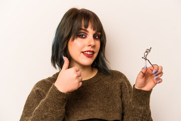 Young caucasian makeup artist woman holding a eyelash curler isolated on white background smiling...