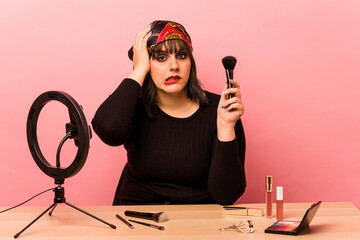 Young makeup artist woman doing a makeup tutorial isolated on pink background being shocked, she...
