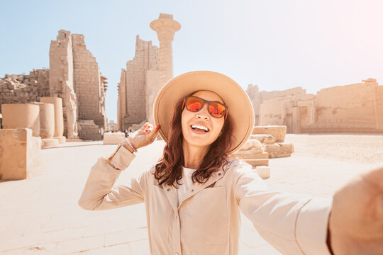Travel blogger woman takes selfie photos at the ruins of the famous Karnak temple in Luxor or ancient Thebes in Egypt.