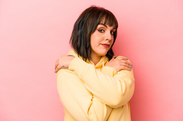 Young caucasian woman isolated on pink background hugs, smiling carefree and happy.