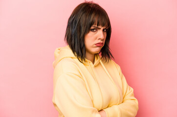 Young caucasian woman isolated on pink background frowning face in displeasure, keeps arms folded.