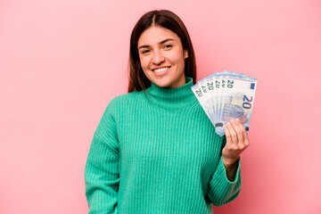 Young caucasian woman holding banknotes isolated on pink background happy, smiling and cheerful.