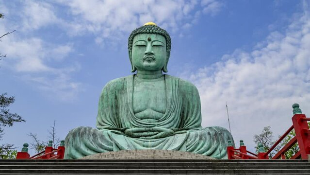 Timelapse of the clouds moving behind the replica statue of the Great Buddha of Kamakura in Japan, at Wat Phra That Doi Phra Chan in Lampang, Thailand