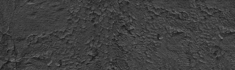 Old weathered black exterior wall wide panoramic texture. Cracked painted plaster. Dark gray grunge widescreen background