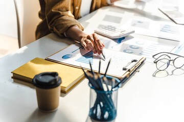 Fototapeta premium Close-up of business woman hands check company finance data reports at desk in modern office.
