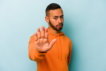 Young hispanic man isolated on blue background rejecting someone showing a gesture of disgust.