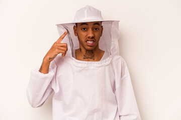 Young African American beekeeper isolated on white background showing a disappointment gesture with forefinger.