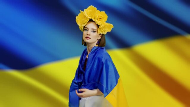 a woman in national clothes looks into the camera with love and anxiety because of the escalation of the military conflict in Ukraine, the Russian invasion against the background of the flag of Ukrain