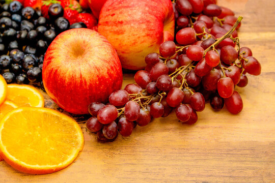 Fresh Fruits Concept, Healthy Fruits Consist Of Grapes Apple Orange And Berry On Wooden Background