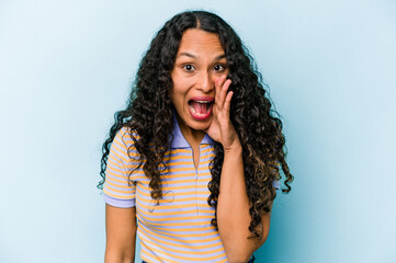 Young hispanic woman isolated on blue background shouting excited to front.