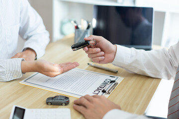 Insurance concept the car dealership giving a car key to his customer after signing the contract