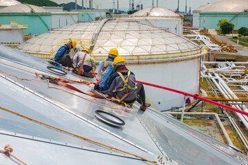 Male workers rope access height safety connecting with a knot safety harness, clipping into roof...