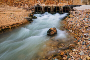 Culvert flowing industrial water slow motion out in release into the sea.