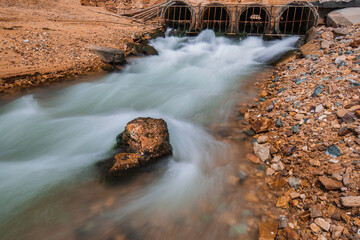 Culvert flowing industrial water slow motion out in release into the sea.