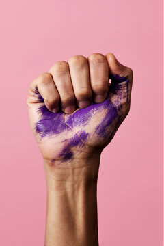 clenched fist with stains of purple paint