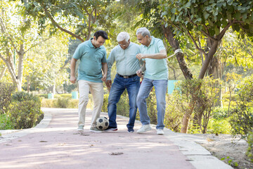 Two senior man with son having fun while playing football at park