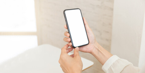 cell phone blank white screen mockup.hand holding texting using mobile on desk at office.background...