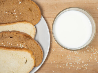Pieces of rye and white bread with a glass of milk on a plate. Healthy breakfast. Bakery products