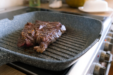 Juicy beef meat steak cooking on griddle pan at professional kitchen. Prime steak frying at grill. Delicious, modern cuisine