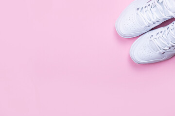 Fototapeta na wymiar White sneakers on a pink background. Place to copy. Healthy lifestyle concept
