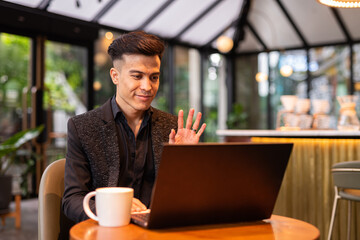 Fototapeta premium Portrait of handsome young businessman using laptop in coffee shop