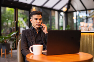 Portrait of handsome young businessman using laptop in coffee shop