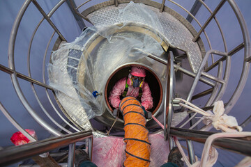 Top view male worker climb up the stairs into the tank stainless chemical area confined space - obrazy, fototapety, plakaty
