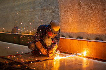 Male worker metal cutting spark on tank bottom steel plate with flash of cutting light close up...