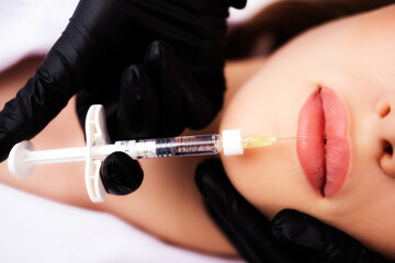 Clinic of plastic surgery. Botox injection. A woman in a beauty salon receives an injection for lip...