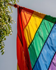 A gay pride flag hangs in front of a store.