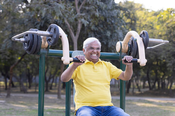 Senior man exercising on pec deck fly machine at park
