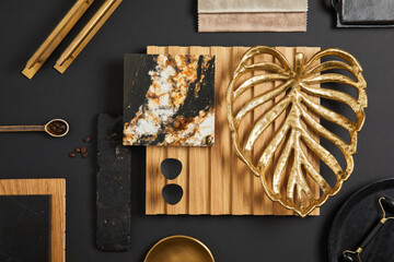 Stylish flat lay comosition of creative architect moodboard with samples of textile, paint, wooden lamella panel and marble tile. Golden, black and beige color palette. Copy space. Template.
