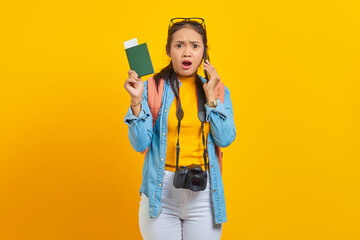 Portrait of surprised young Asian traveler holding boarding pass passport ticket and talking on smartphone isolated on yellow background. Passengers traveling on weekends. Air flight travel concept