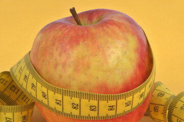 Pomme entour&eacute; d'un m&egrave;tre souple en gros plan sur fond jaune