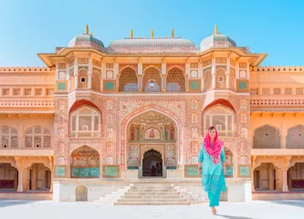 Fotobehang An Indian woman dressed in traditional costume walks between columns - Columned hall of Amber fort - Jaipur, Rajasthan, India © muratart
