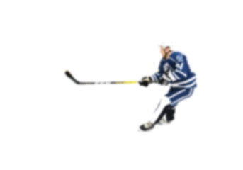 Obraz premium Hockey player in blue uniform in motion on the ice - out of focus hockey player on ice - blur hockey match on background