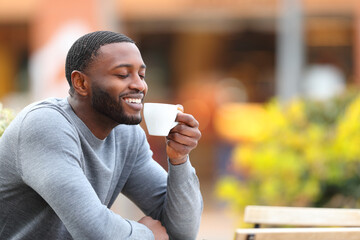 Happy man with black skin drinking coffee in a bar