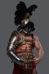 Shot of handsome greek warrior with nude muscular body showing his strength against grey background.