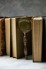 old books and magnifying glass on table, abstract background. concept of search, mystery,...
