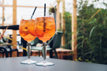 Two glasses of Aperol Spritz served on the terrace of modern bar. Popular Italian wine based...
