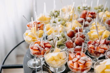 Various fresh fruits and berries in glasses at a party reception. Healthy dessert concept.