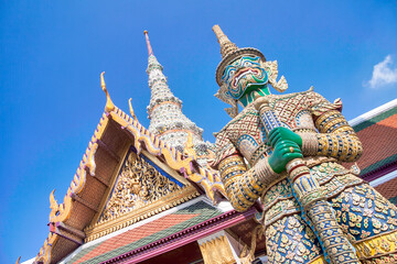 Roofs of Wat Phra Kaew (Temple of the Emerald Buddha) and face of the yaksa Thotsakhirithon, giant...