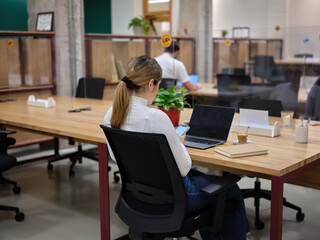 woman with her mobile phone sitting in a coworking space with other people