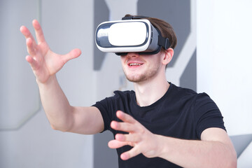 Portrait of happy cheerful young handsome man, positive smiling guy using, wearing a modern device virtual reality headset mask or 3D, AR, VR glasses, playing the game. People and technology concept.