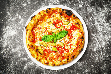 Top view of vegetarian pizza with zucchini and pepper on dark background.