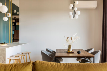 Modern and vintage dining room with brown wooden table, grey chairs and stylish chandelier....