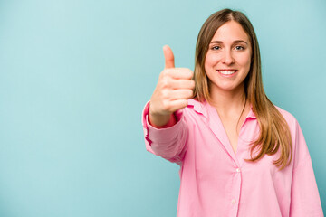 Young caucasian woman isolated on blue background smiling and raising thumb up